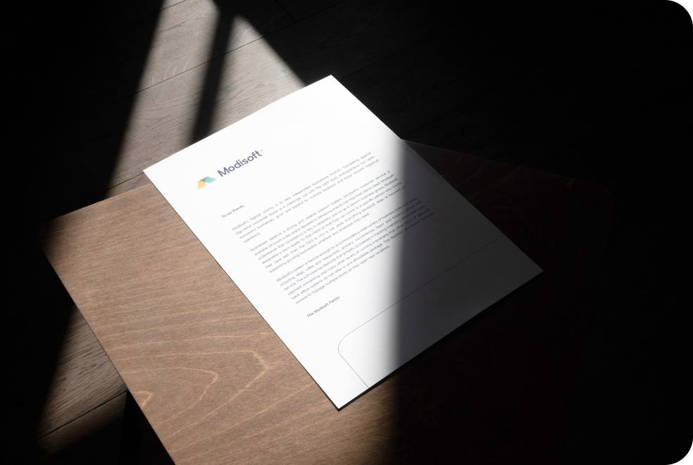 Modisoft business letter on a wooden desk highlighted by natural light, showcasing professional branding and corporate communication materials