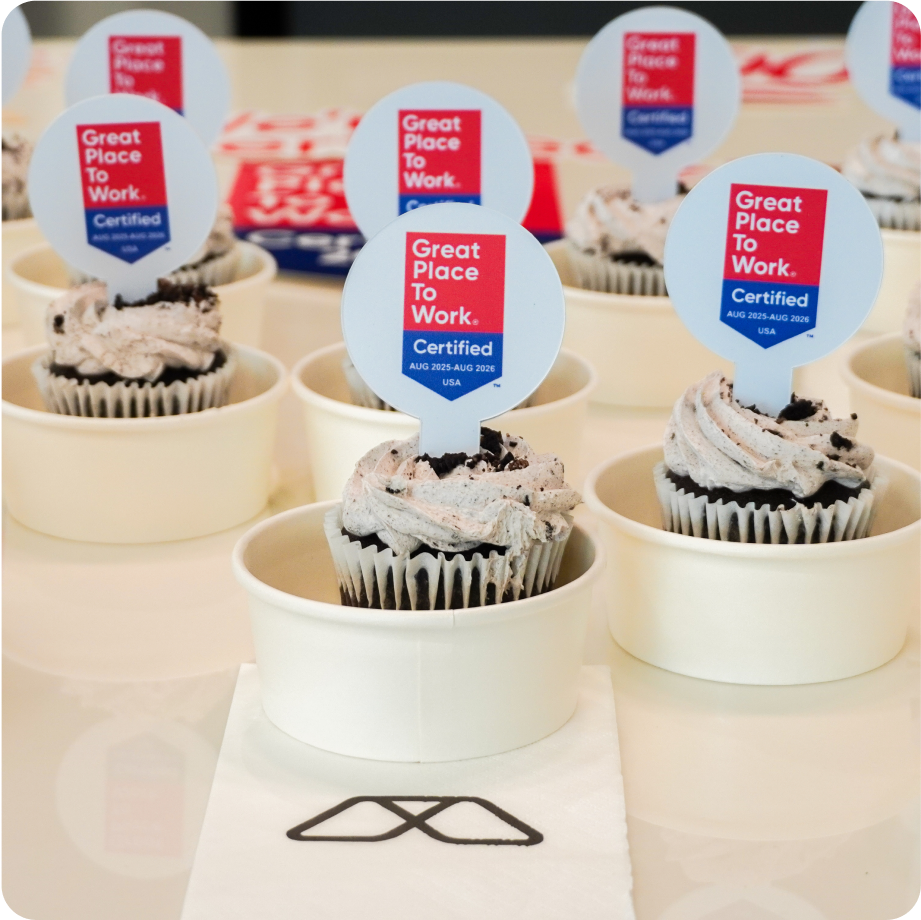 Cupcakes topped with Great Place to Work Certified 2025 USA toppers displayed during a celebratory event.