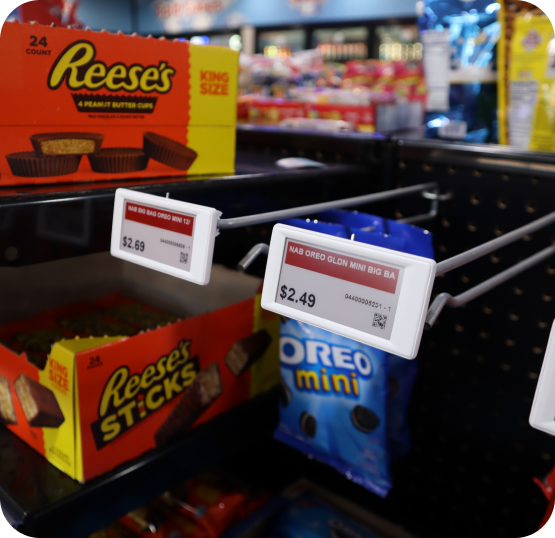 Retail product display featuring electronic shelf labels with pricing information and packaged snack products on store shelving.