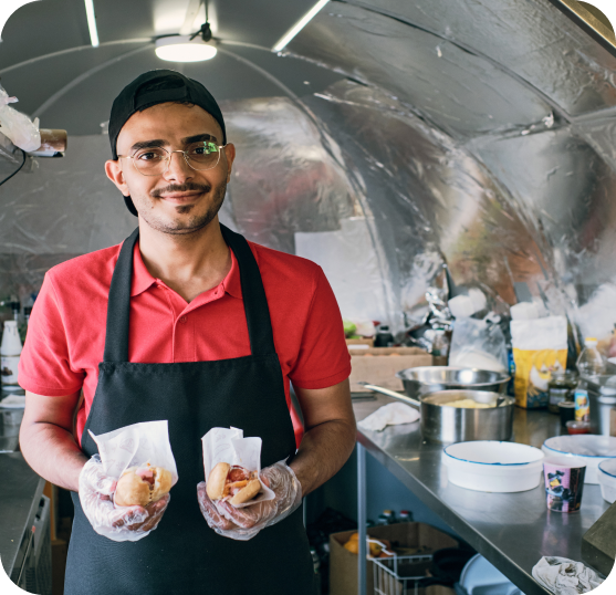 Food service worker holding prepared food items inside a food truck kitchen.