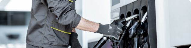 Fuel station worker operating fuel pumps during a vehicle refueling process.