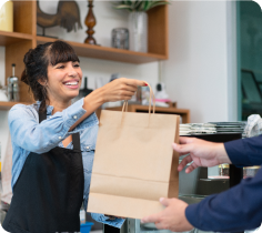 Retail transaction scene with a shopping bag being handed to a customer at a checkout counter.
